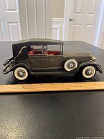 Close-up photo of a large vintage toy car with a soft convertible roof, detailed whitewall tires, and a red interior seat showing side view