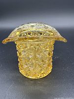 Front side view of yellow cut glass candle holder showcasing intricate star and diamond cut pattern with flared top edge.