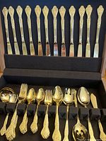 Stanley Roberts gold electroplated flatware in a fitted case including knives, forks, spoons, and serving utensils with detailed patterned golden handles