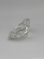Close-up of a clear, diamond-shaped faceted Swarovski crystal paperweight with sharp angles and polished facets.