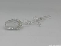 Clear crystal rose figurine shot from side angle showing stem and two leaves.