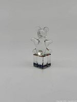 Front view of clear crystal Swarovski bear figurine standing on a square crystal base, showing the bear's face, ears, arms, and legs.