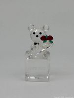 Front view of the clear faceted crystal bear holding the red and green bouquet on the engraved crystal cube with 'I LOVE YOU' text