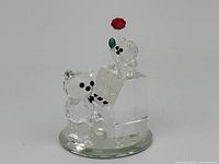 Front and right side view of Swarovski miniature bears with piano figurine on clear oval base.