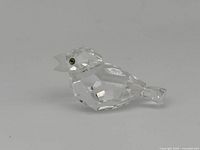 Side view of the clear crystal bird figurine showing the faceted body and frosted beak