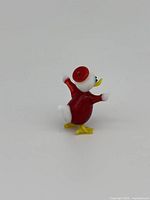 Photo showing the duck figurine from side angle highlighting the red body and white head with yellow beak and feet