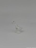 Front-left angle view of Swarovski miniature goose figurine on a plain background showing clear multi-faceted crystal design and black eyes.