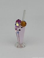 Front angle view of Swarovski miniature ice cream soda figurine showing pink faceted glass and colorful crystal scoops with clear straw.