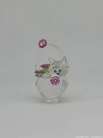 Front view of Swarovski crystal kitten in flower basket, displaying the kitten with blue eyes and pink flowers on basket handle.