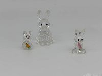 Front view of the three Swarovski crystal miniature rabbit figurines showing details of size and colored crystal carrot and flower elements.