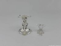 Two Swarovski miniature spotted dog figurines, one large and one small, side by side on white background