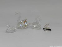 Front view of four Swarovski crystal swans showing sizes and clear crystal detailing.