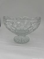Front side view of clear crystal footed bowl showing detailed cut crystal patterns, scalloped rim, and pedestal base.