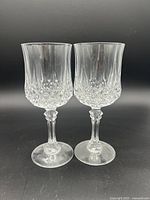 Two vintage Cristal D'Arques Longchamp crystal glasses with textured bowls and decorative stems on black background.