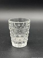 Side view of the vintage shot glass showing the textured geometric pattern and thickness of the clear glass.