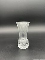 Full view of the vintage Fostoria glass bud vase showing the flared top and ribbed body transitioning into the thumbprint design base.