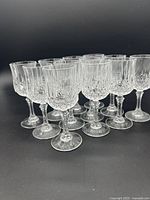Front angle showing all 12 vintage cordial glasses arranged in rows, highlighting the clear textured glass pattern and stems.
