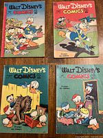 Four Dell Walt Disney's Comics and Stories comic issues from late 1940s to early 1950s laid out flat, showing front covers with Donald Duck and nephews artwork.