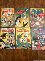 Six Walt Disney’s Donald Duck comic books laid out on wooden surface.