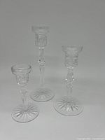 Photo of three clear Waterford crystal candlestick holders of varying heights with starburst bases and cut crystal detailing.