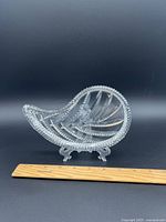 Crystal leaf-shaped teardrop dish photographed with a ruler for size reference showing clear cut crystal design and textured edge.