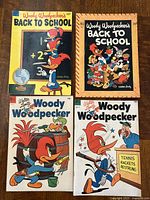 Four Woody Woodpecker comic books with colorful covers showing Woody at school, fishing, and tennis.