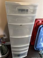 Front view of the tall plastic storage container showing all seven drawers and a white top lid.