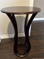 Full view of the accent table showing the curved supports and round base.