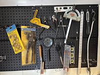 Tools hung on pegboard including saw, pliers, levels, magnifier, protractor, and wrench