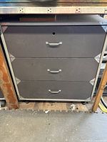 Gray metal cabinet with three drawers in workshop setting