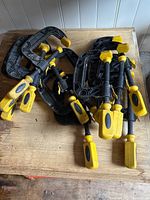Metal C-clamps with large yellow handles, showing multiple clamps stacked together.