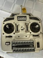 Top view of Futaba remote control transmitter showing dual sticks, various control switches, frequency dial, and model control device slots