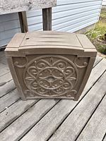 Closed view of the garden hose container showing decorative front panel design with a circular pattern.