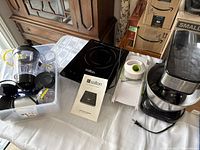 Photo showing Salton induction cooktop, Magic Bullet blender parts in storage bin, mandolin slicer and pineapple cutter on table.