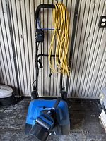 Blue and black Kobalt electric snowblower with long yellow extension cord coiled on handle.