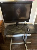 Front view of Lenovo ThinkCentre monitor on a mobile black desk with Lenovo keyboard and Acer mouse present