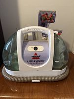 Front view showing Bissell Little Green TurboBrush with power button and water tanks.