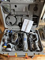Photo of the entire spin saw kit in the open carrying case showing the tool, handles, attachments, and instruction manual inside the molded compartments.
