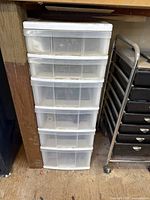 Plastic storage container with 6 drawers filled with items