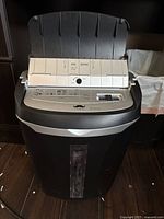 Front view of black and silver Mustache ShredderMax paper shredder showing the feeding tray and control panel.