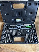 Open view of tap and die set showing dies, taps, and handle tools arranged in plastic case.