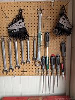 Combination wrenches and screwdrivers hung on pegboard