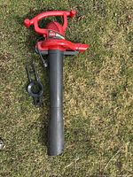 Full view of red Toro Ultra Blower Vac with black nozzle and detached metal impeller accessory on grass surface.