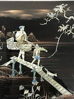 Close-up image of the lacquer panel showing the detailed mother of pearl inlay of a man, child, dog on a plank bridge.