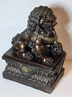 Front three-quarter view of bronze Fu Dog on ornate base
