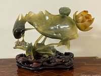 Front angle view showing lotus leaf, bird and blossom atop wave-form wooden stand