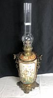 Full front view of entire oil lamp showing ceramic body, brass mounts and glass chimney