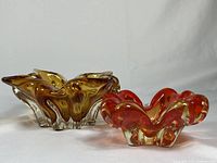 Photo showing side-by-side amber and orange ruffled vintage glass candy dishes on white background.