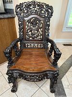 Full front view of hardwood Chinese carved armchair showing dragon crest, openwork backrest, arms and seat.