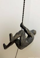 Close-up of cast iron figure gripping twisted metal rope